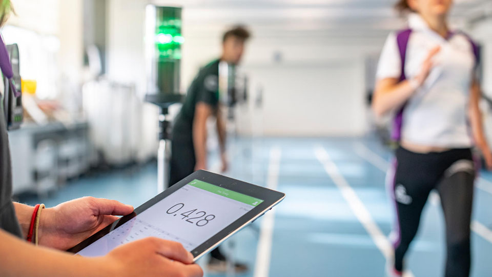 A student at Loughborough University who is running on a track and using an iPad